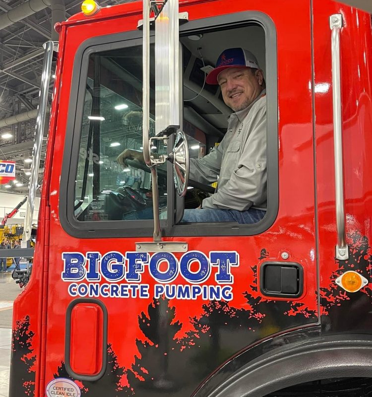 Paul Landreth smiling from a cab on a Bigfoot Concrete Pumping truck